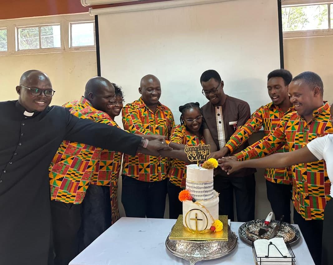 The chaplain and choir members cutting the Choir Day cake at the commissioning of new members
