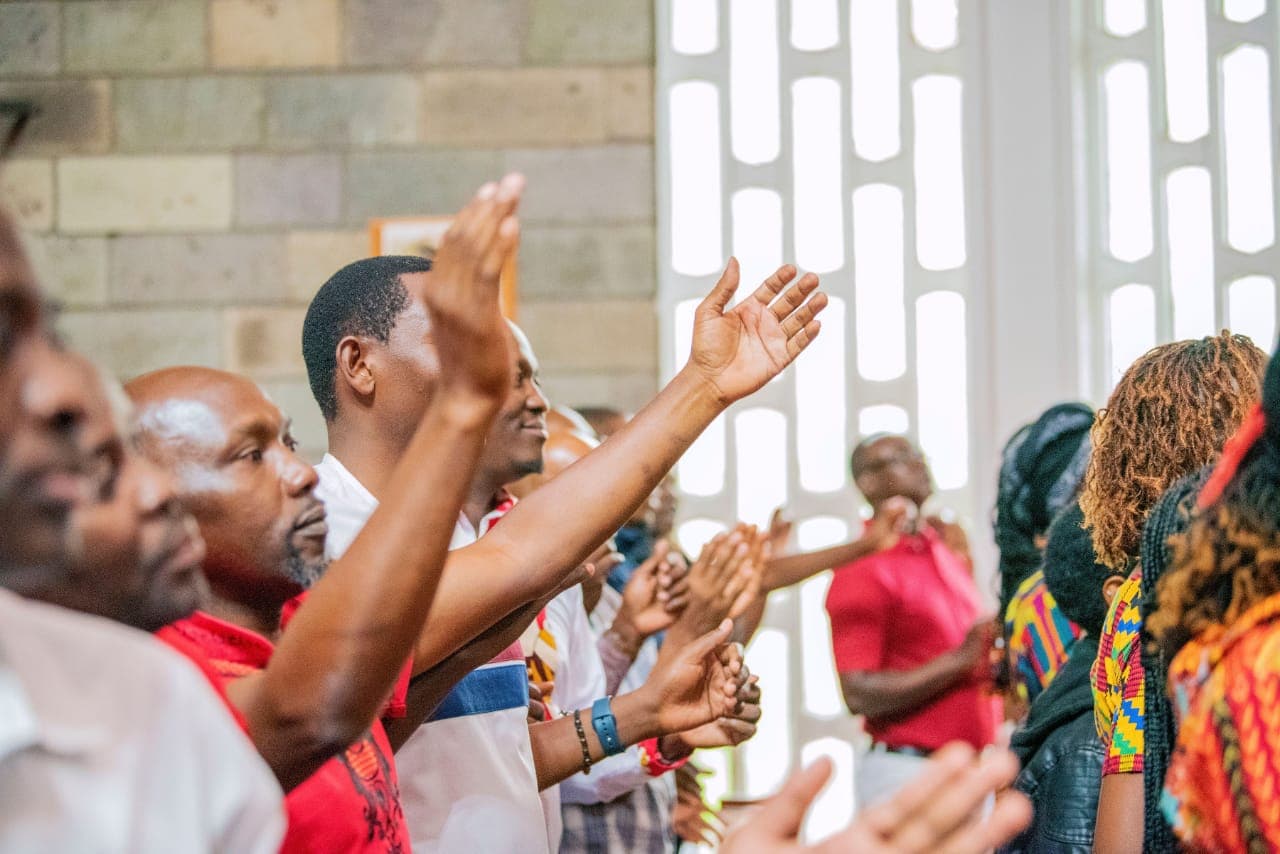 Choir members with hands raised in praise during Sunday Mass at St. Paul's University Chapel